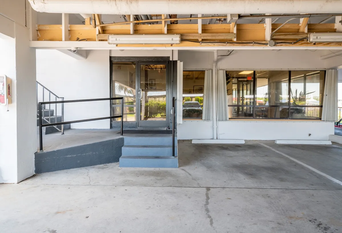 The image shows the entrance to the property, with steps leading up to a welcoming front door framed by large windows. The exterior gives a sense of arrival and security, and hints at the comfort within.